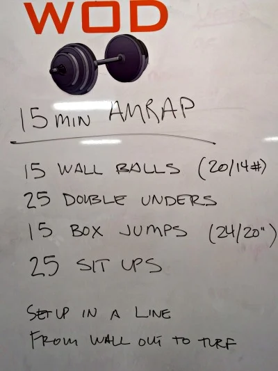 Gym whiteboard reading 15 min AMRAP with four movements